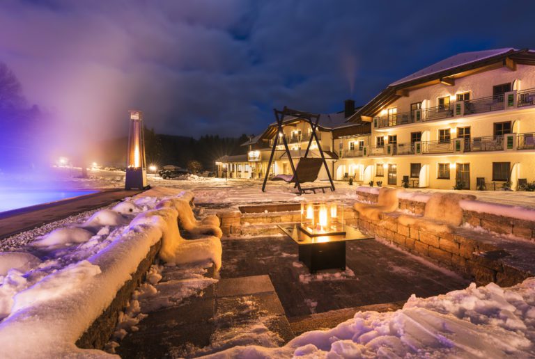 Außenbild des Hotel Hammerhof bei Nacht im Winter mit Schnee mit leuchtenden Lichtern und Laternen